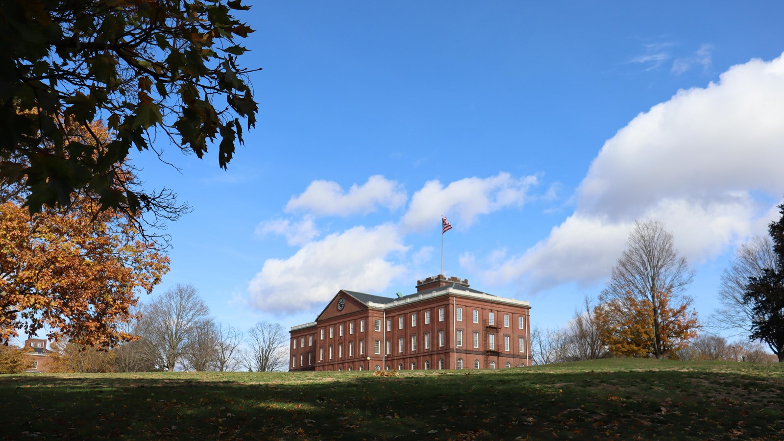 The Main Arsenal Building,  on a hill with a blue sky and clouds with trees framing the image.