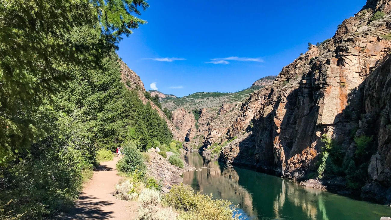 A footpath along a narrow canyon with water and trees