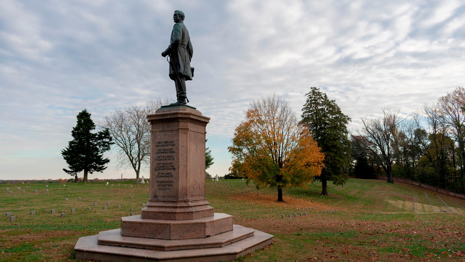 A stone monument with a Union soldier atop a rectangular base in a cemetery.
