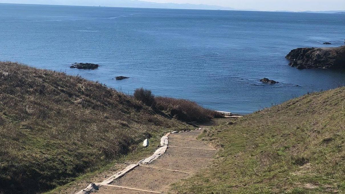 Trail down to Grandma\'s Cove, a sandy beach. It\'s sunny and the water is blue