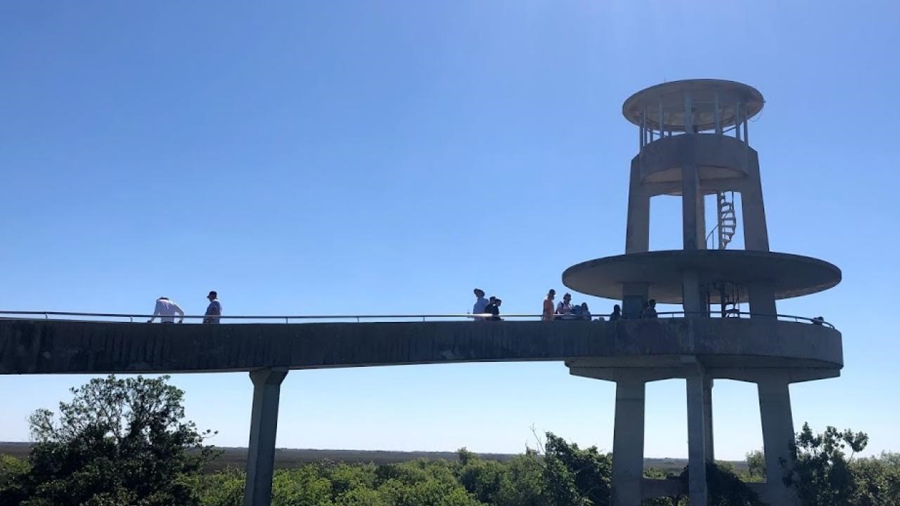 Spiraling concrete observation tower is silhouetted against a bright blue sky