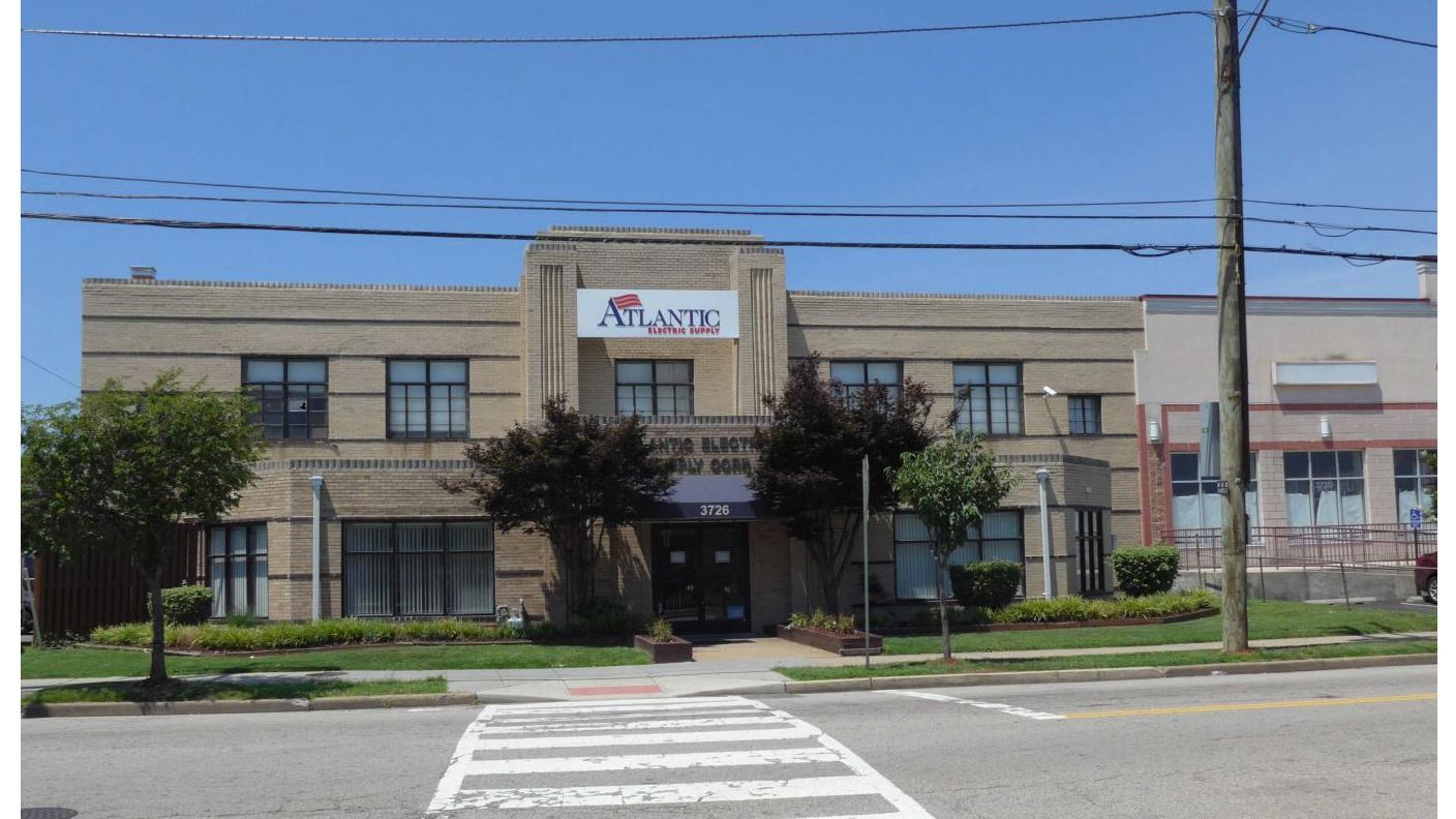 two story brick building facing the street with a center entrance and symmetrical wings 