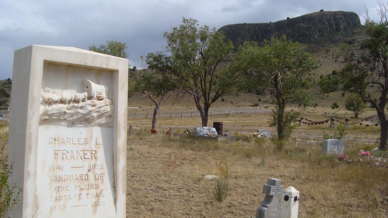 A cemetery gravestone with a distant tall butte.