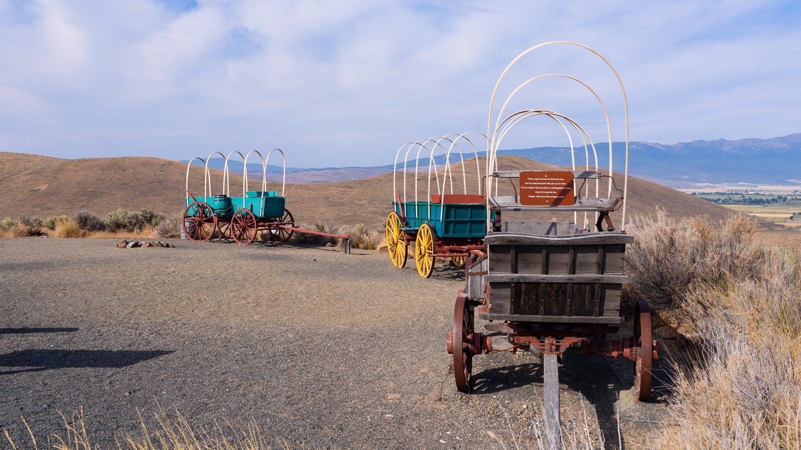 Wooden wagons sit uncovered in a desert setting.
