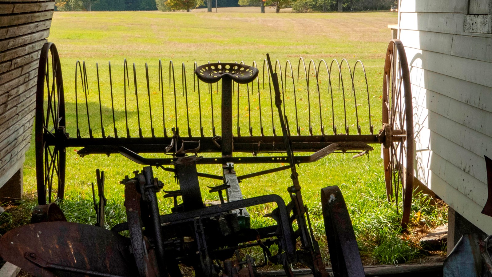 Vintage farm equipment is silhouetted against a bright green grassy field