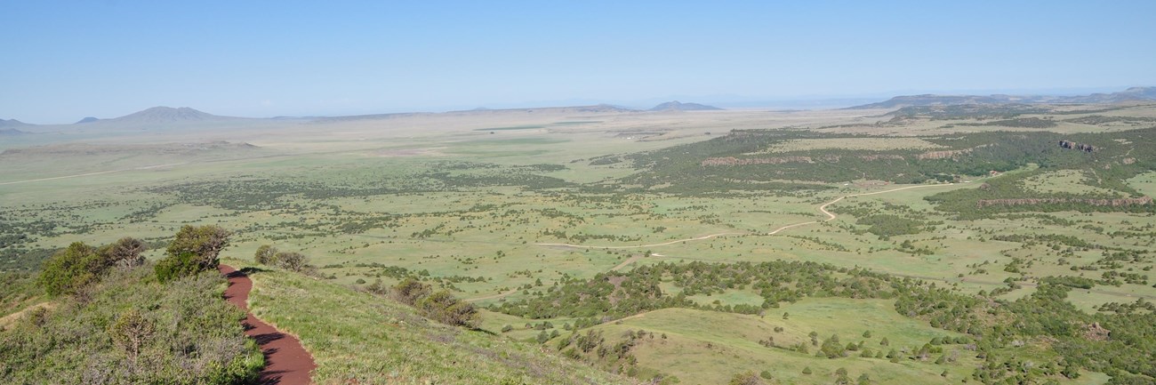 View of the Rim Trail to the left and the prairie and other volcanoes in the distance from the top