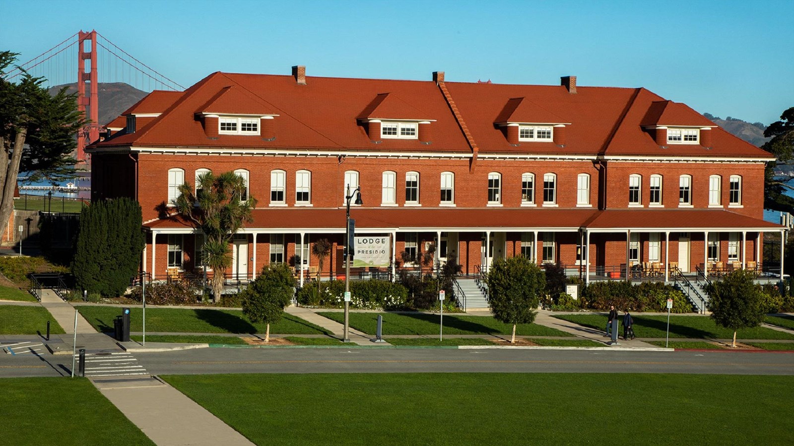 Large, three story, red bricked building with many windows and a green grass lawn in front