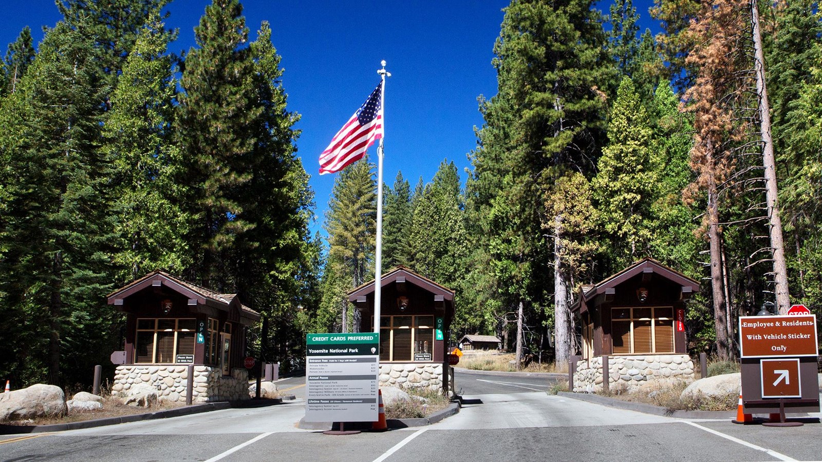 Three small wooden buildings at the entrance with the American flag on a pole