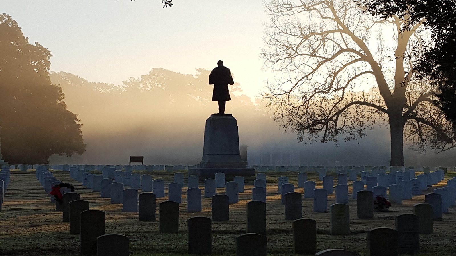 Statue of a soldier standing over graves in a cemetery