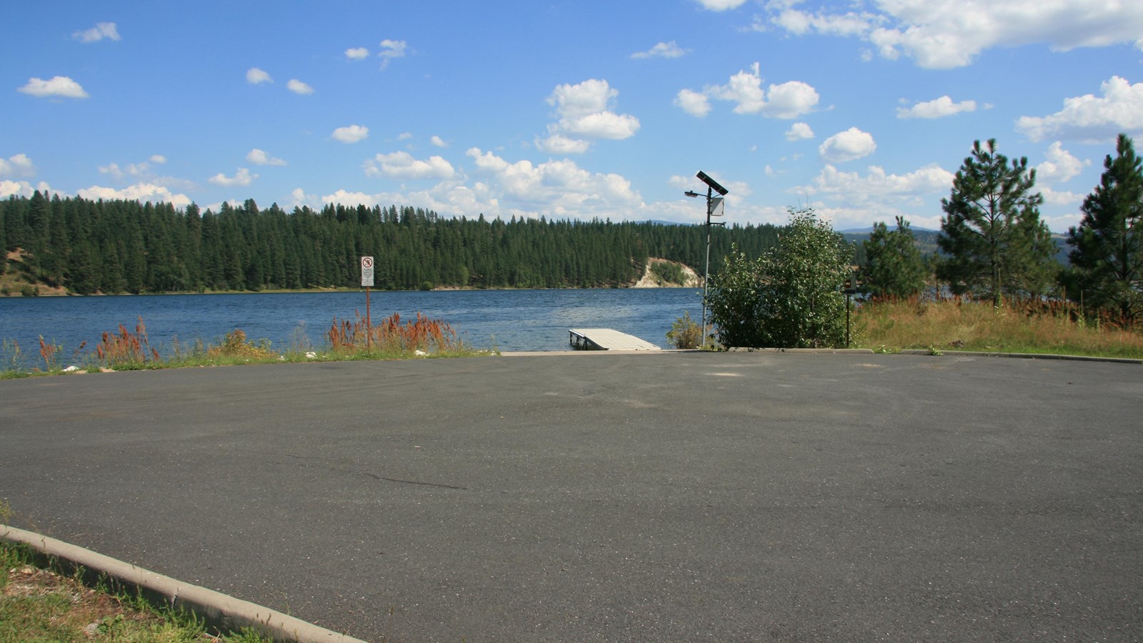 The paved boat launch and dock area at Snag Cove with the wooded shore beyond.
