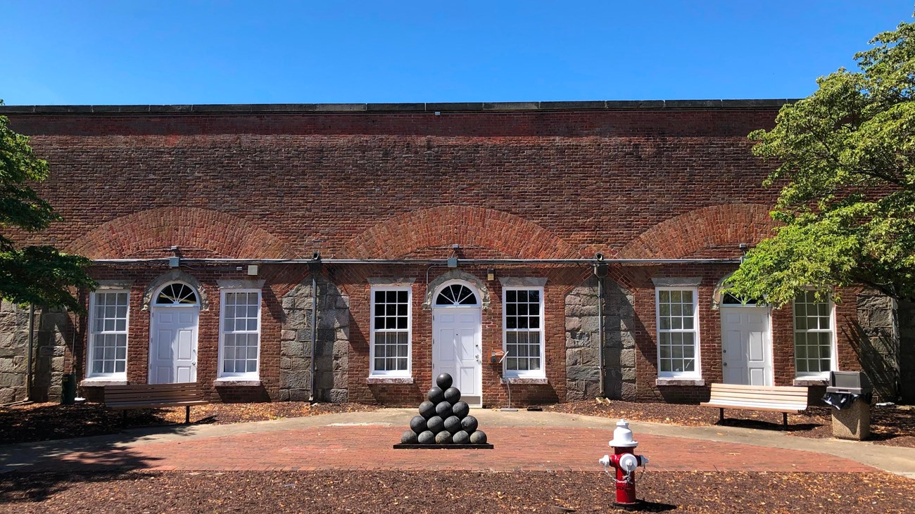 A pyramid of stacked cannon balls marks the entrance to a museum built into a brick fort.