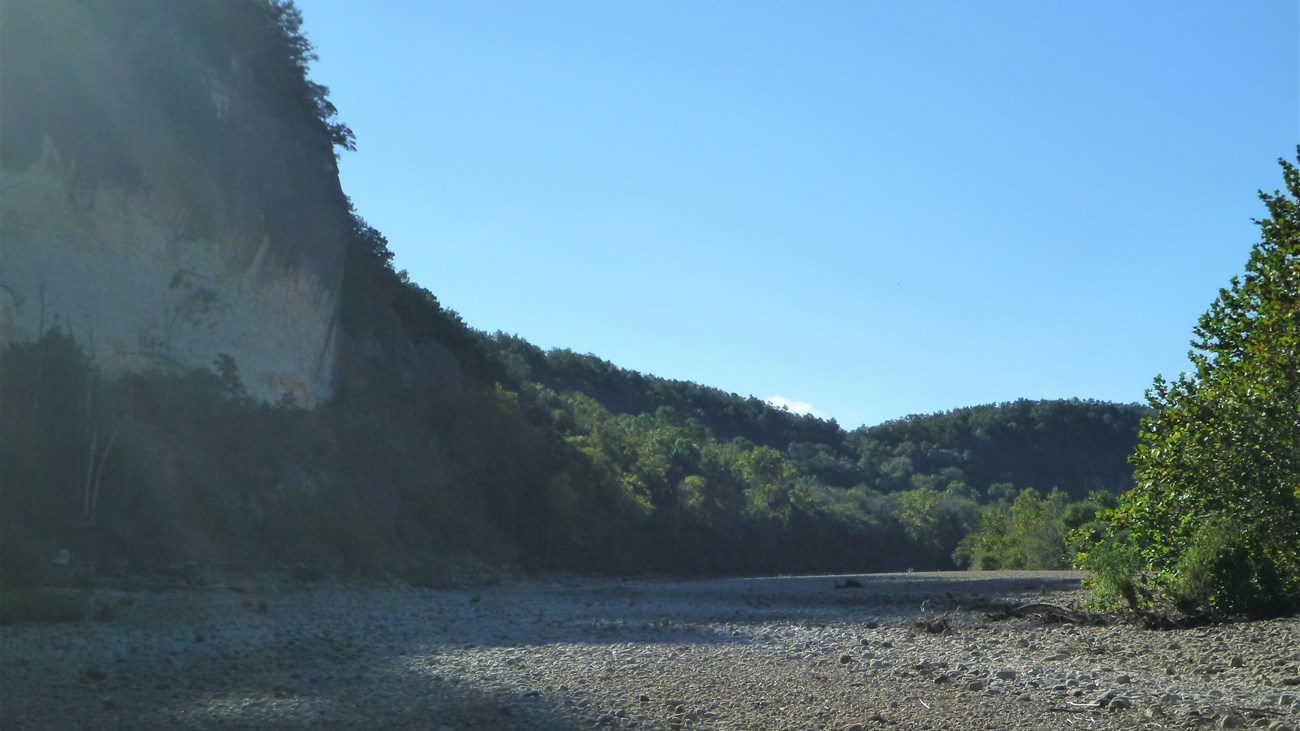 grey gravel with shadow from tall grey bluff at left