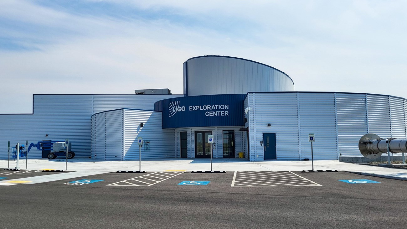 White modern museum with blue entryway and white lettering: “LIGO Exploration Center.”