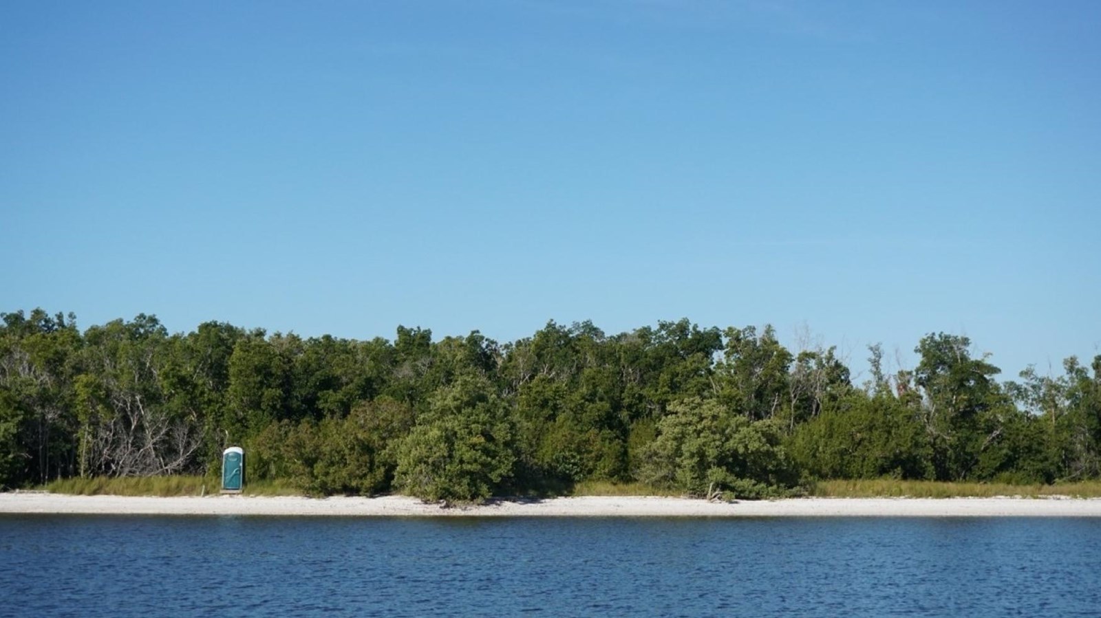 White sandy shoreline with blue water and green vegetation covering the land.