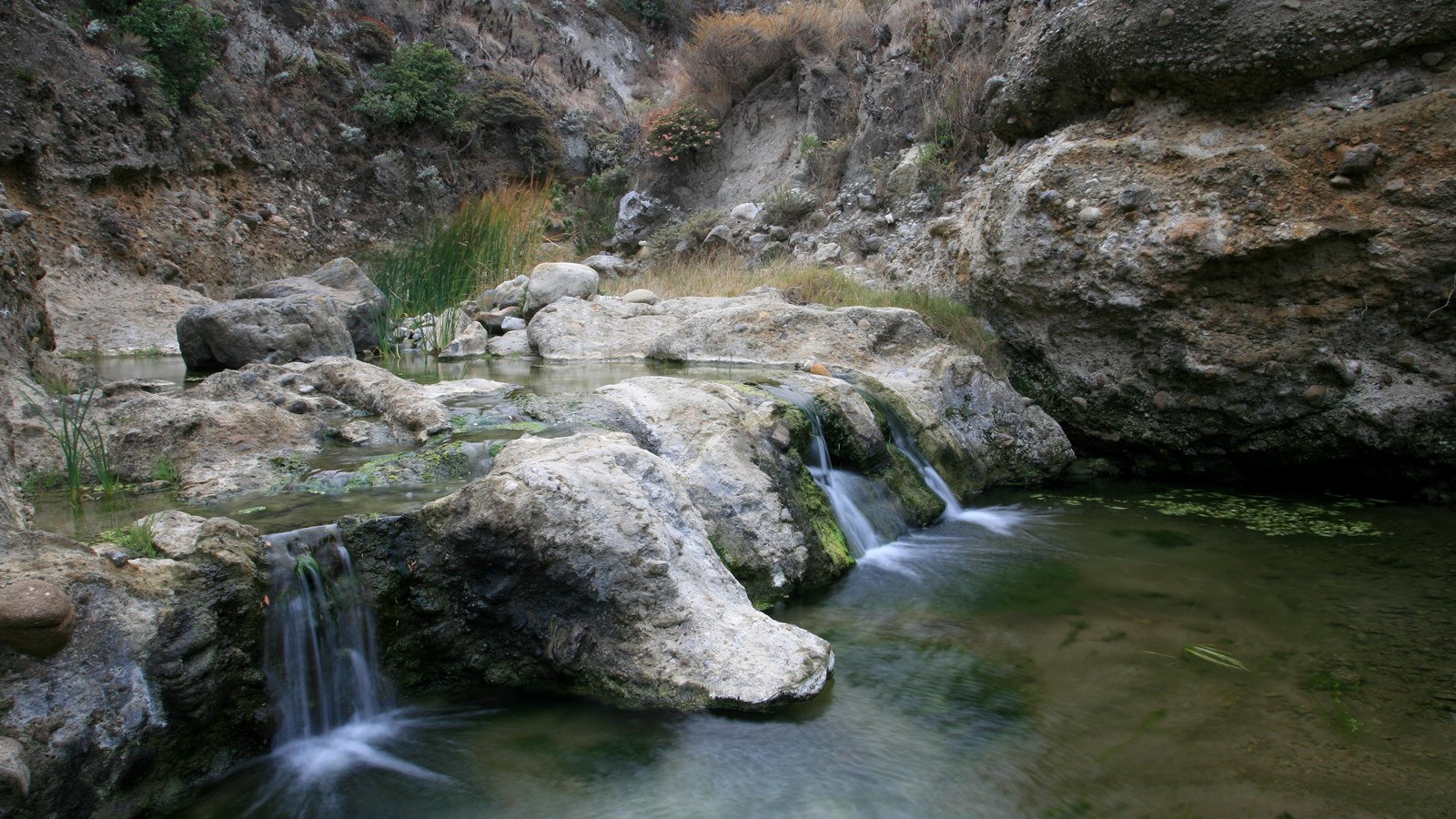 creek cascading over a small fall in a canyon with steep walls. 