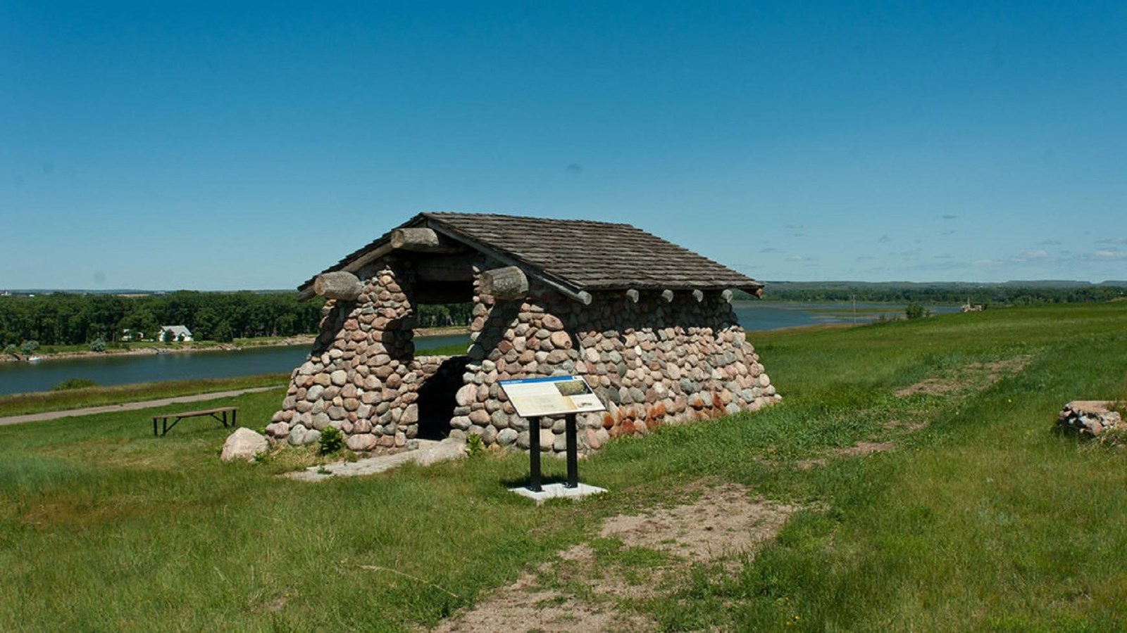 A fieldstone structure with an interpretive panel along the shore of the Missouri River