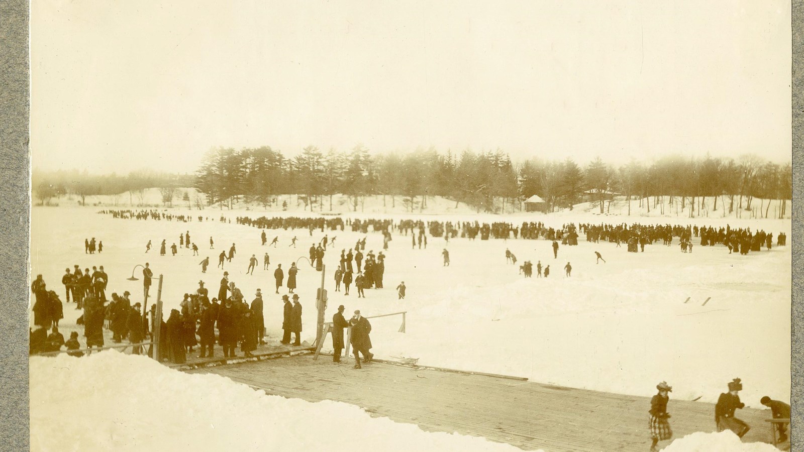 Black and white of flat area covered with snow and ice with many people standing on it