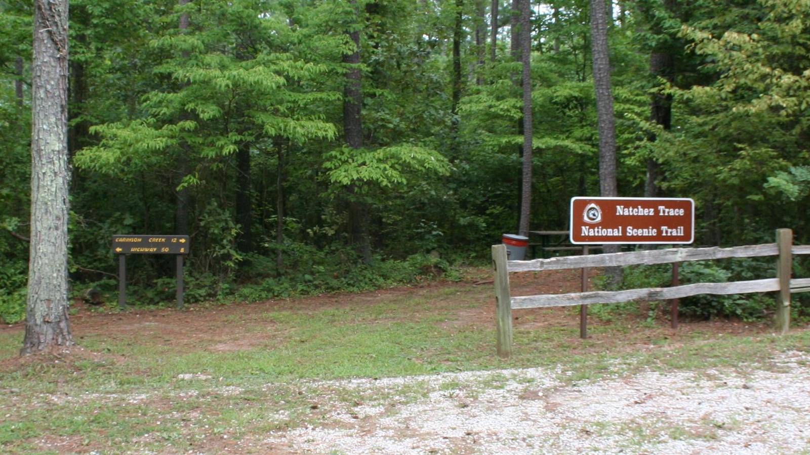 Trailhead and parking. Trailhead is separated from parking with a wooden rail fence.