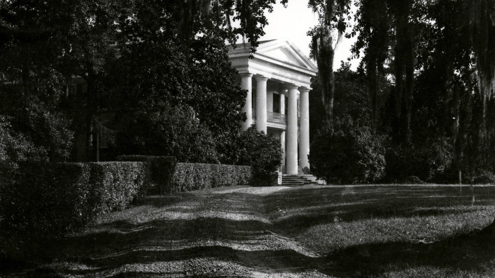 Greek revival syle mansion featuring four columns and an upstairs and and downstairs proch.