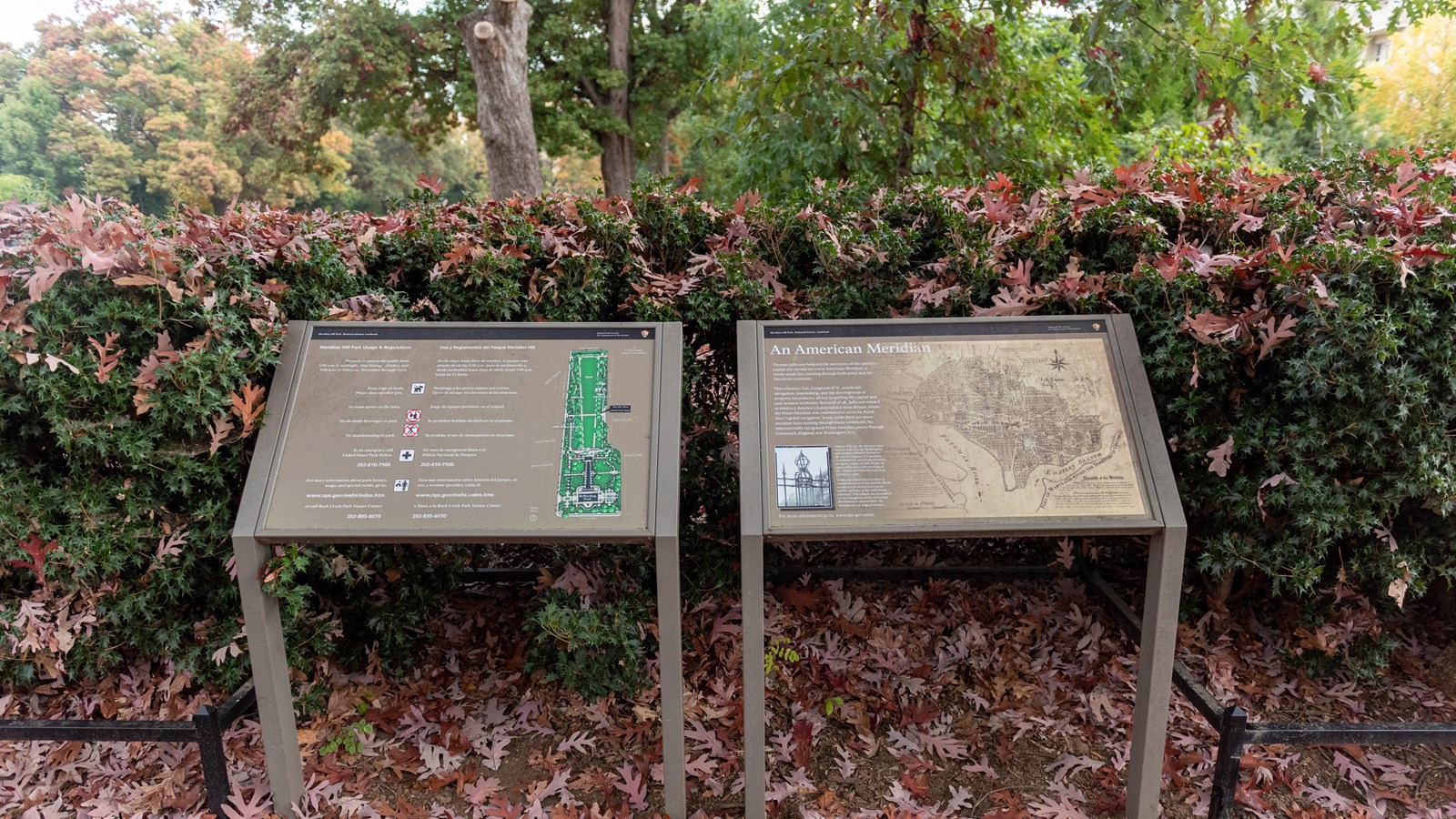 Two informational panels in front of a shrub