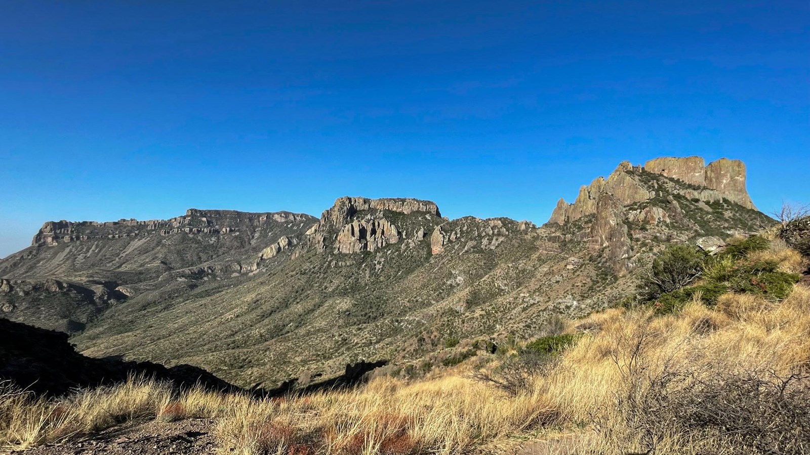 A view to the south encompasses two high peaks and a high, long series of cliffs.