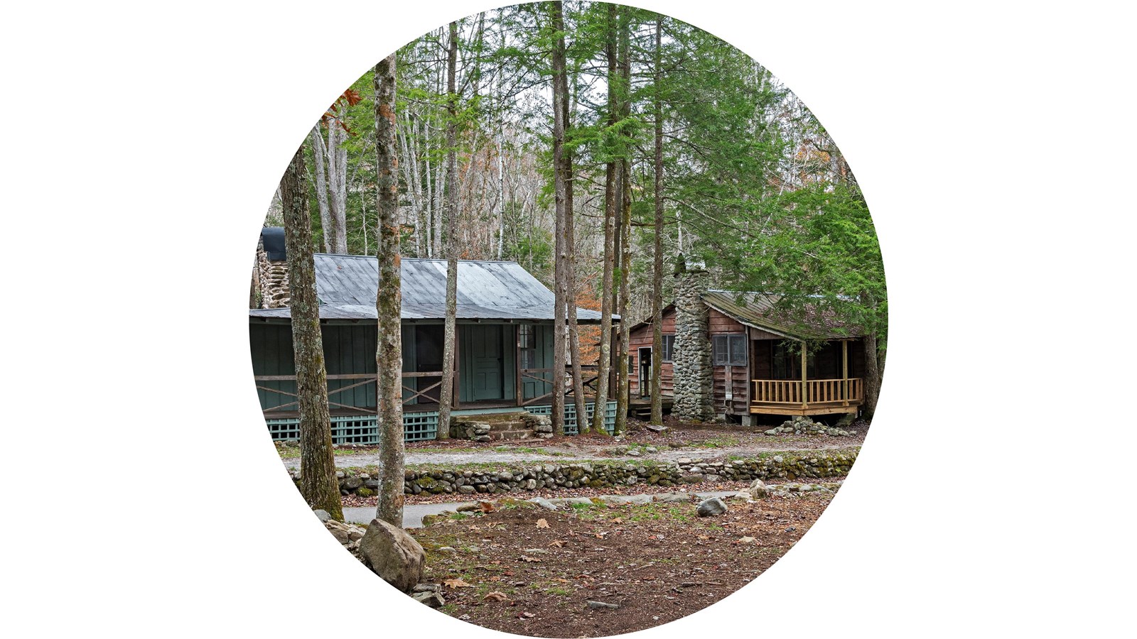 Historic buildings in a row surrounded by trees. Buildings have covered porches and stone chimneys.