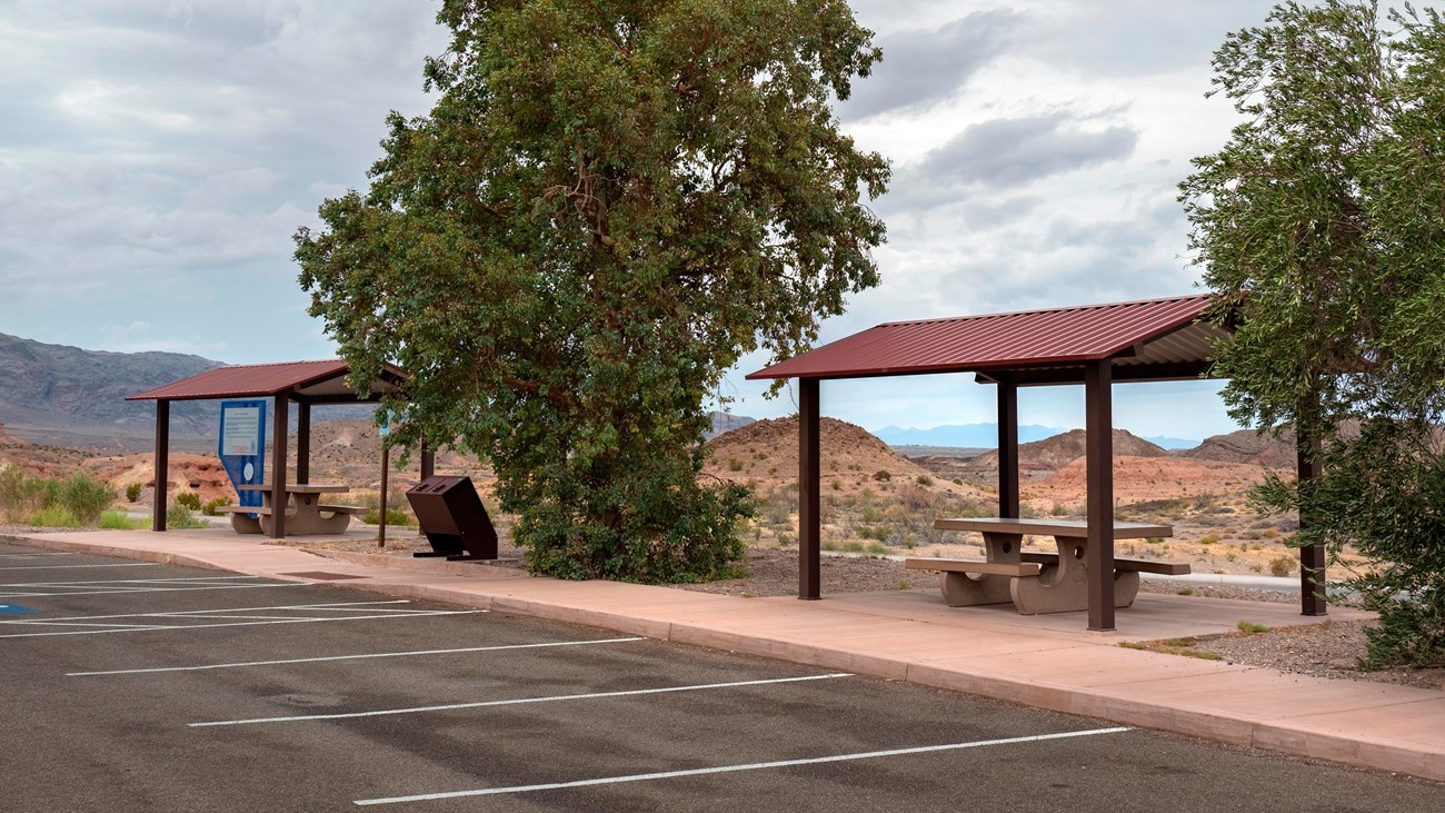 Two picnic shelters next to a parking lot