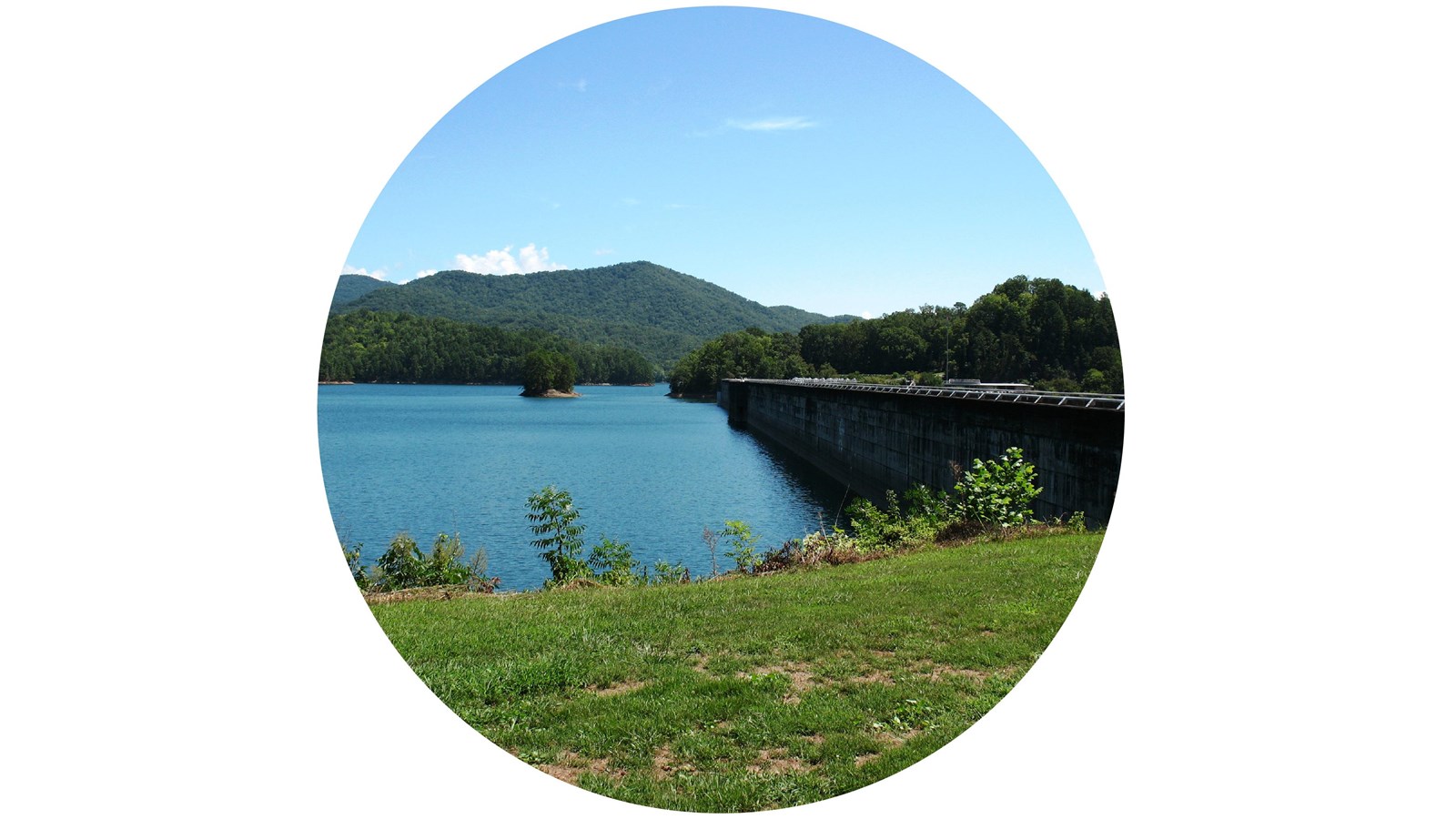 Water beside a dam with a mountain view in the background.