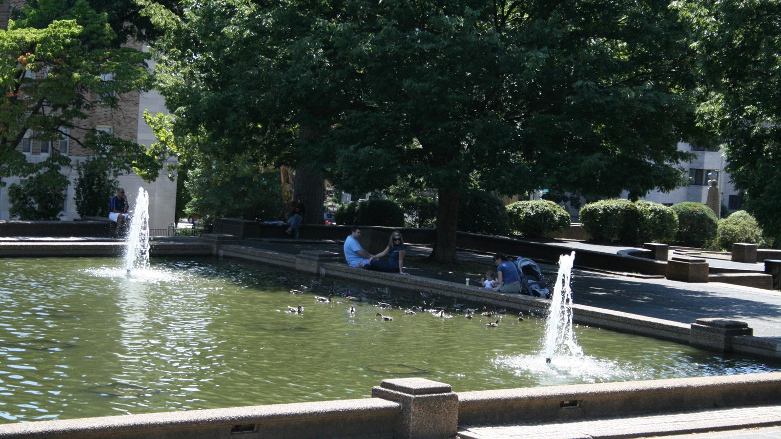 People lounge around the edge of the reflecting pool and fountains in Meridian Hill Park