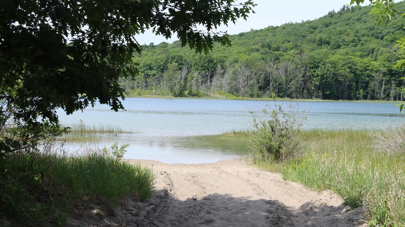 A scenic view of Bass Lake North, a sandy two-track leading to the shore. Water rippled from wind. T