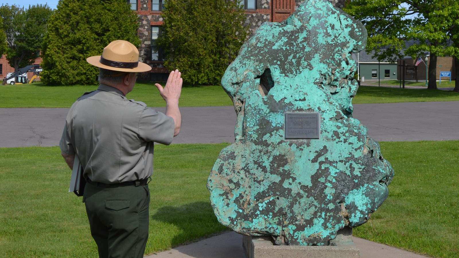 A ranger faces a specimen of float copper with a teal patina displayed on a concrete platform.