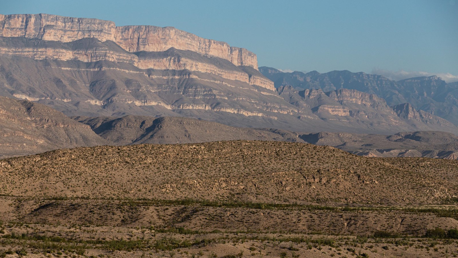 A view across low hills to the Sierra del Carmen mountains rising along the skyline.