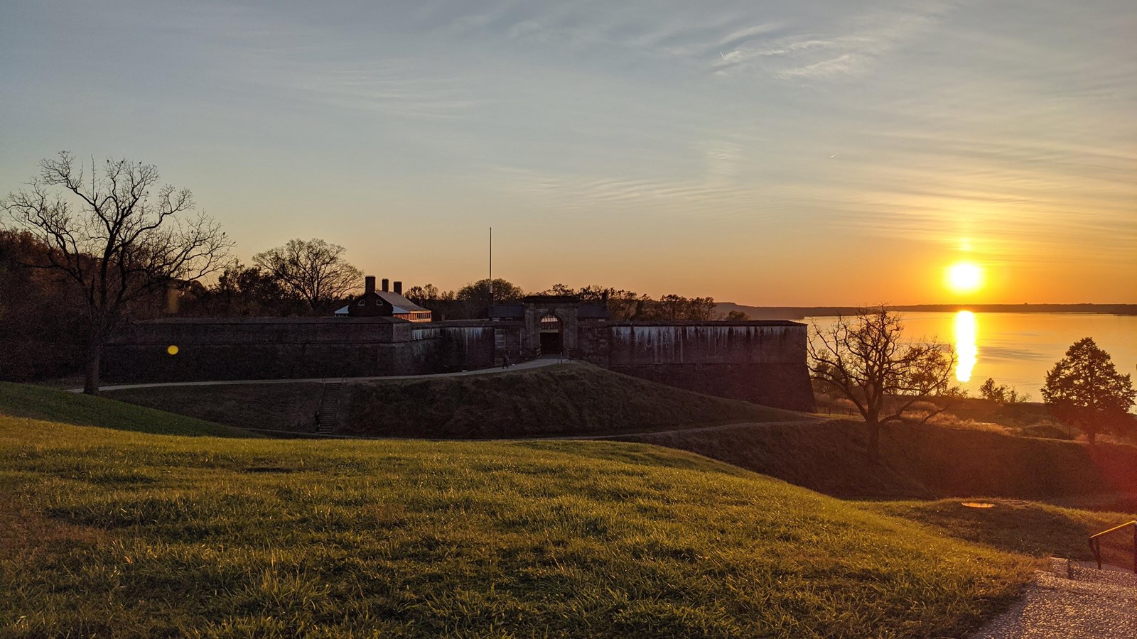 a brick and stone fort atop a hill, overlooking the Potomac River at sunset