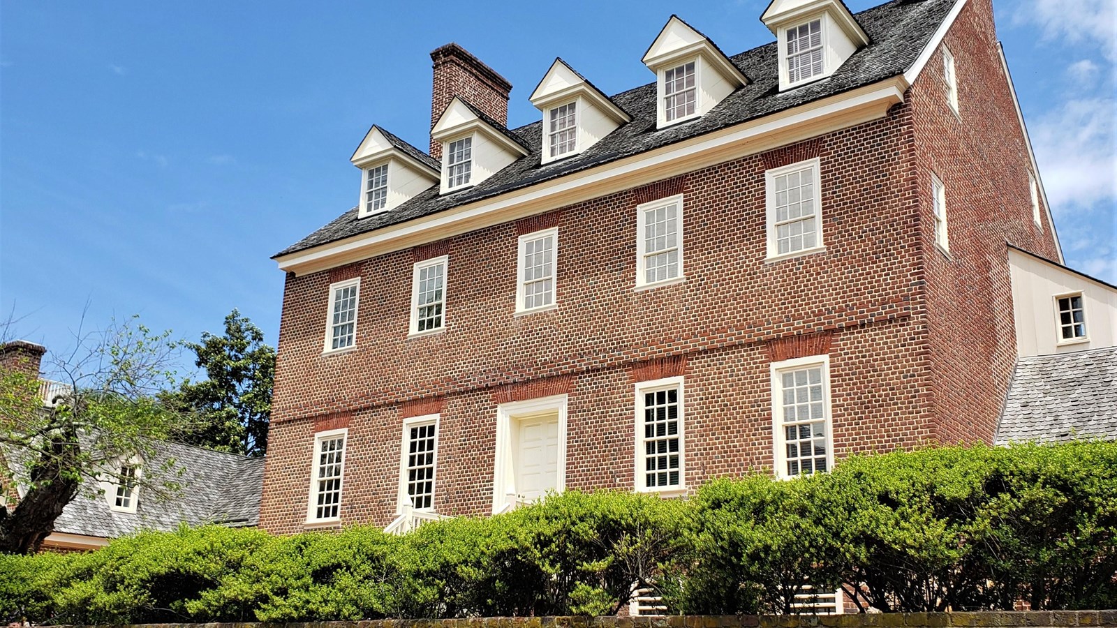 A red brick building against a blue sky with a few clouds. 