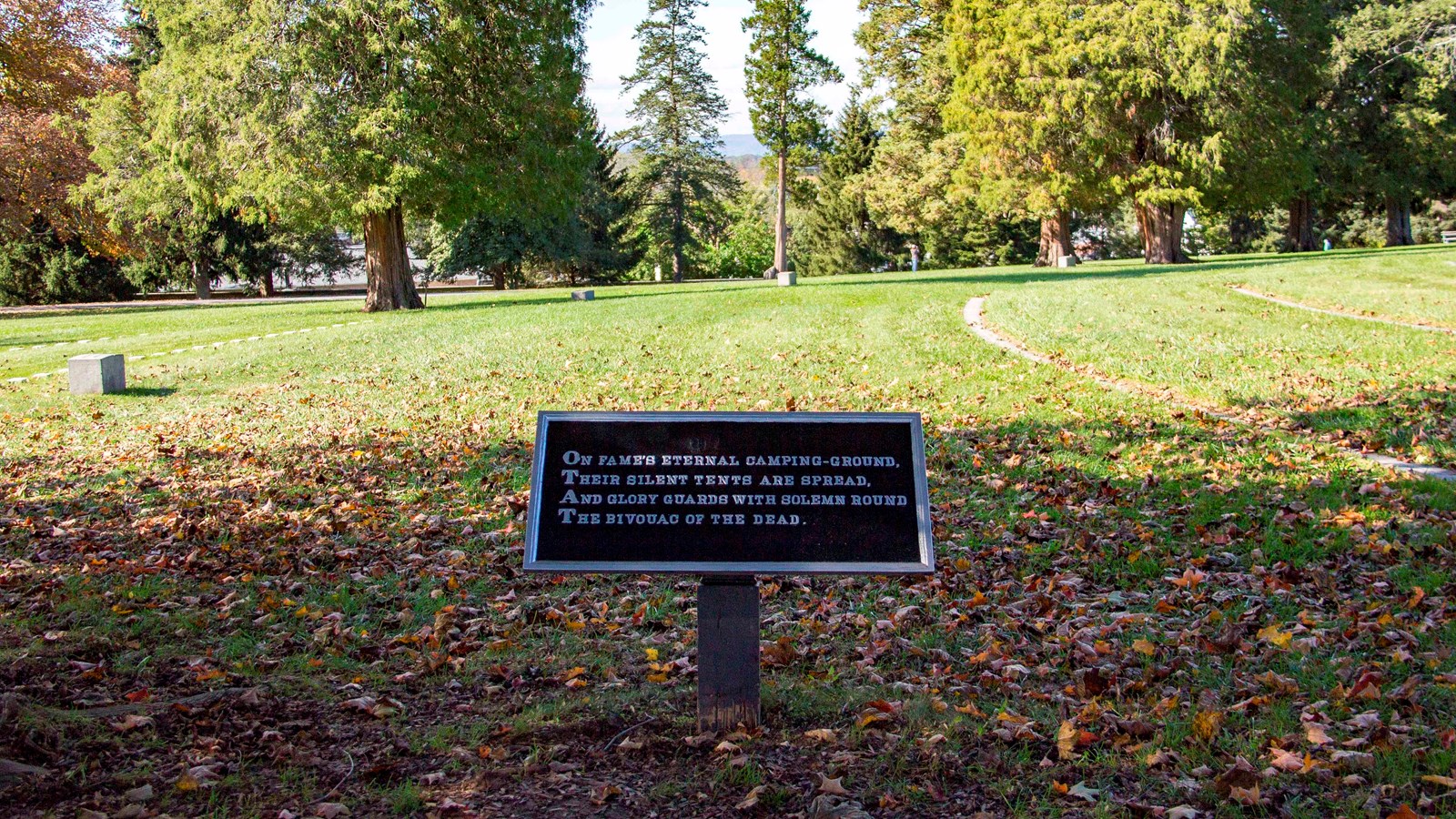 A black and white plaque with a poem stanza in a cemetery 