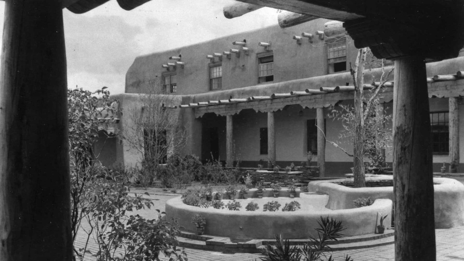 A historic black and white photo of a two story, adobe building.