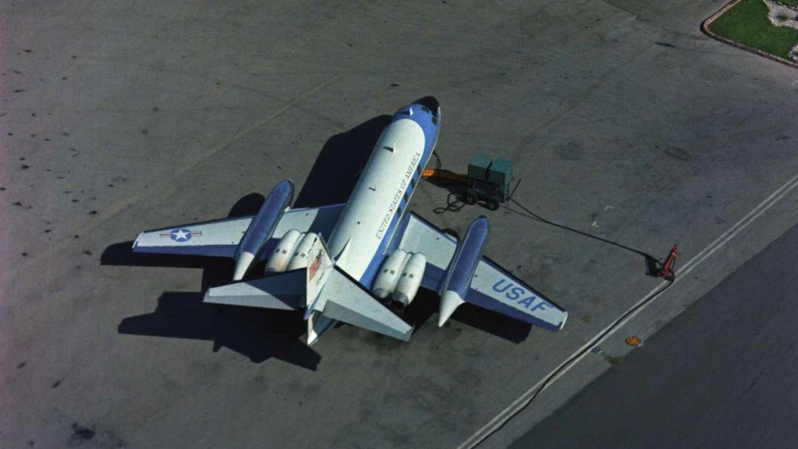 Looking down on asphalt, there sits a small white and blue plane.