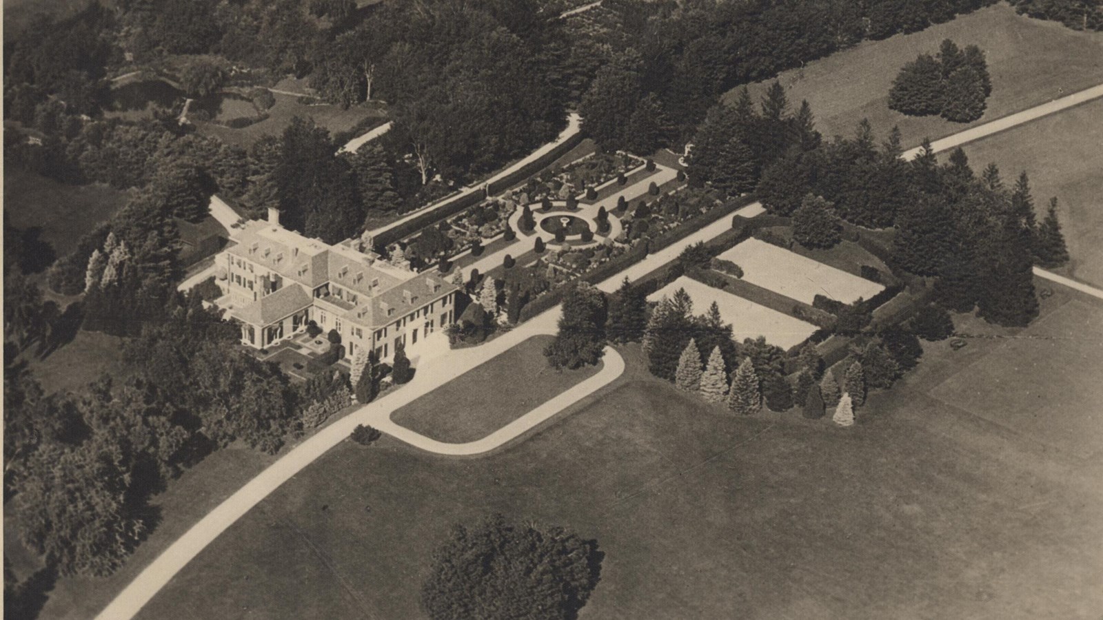 Aerial of large home with garden area and many trees around
