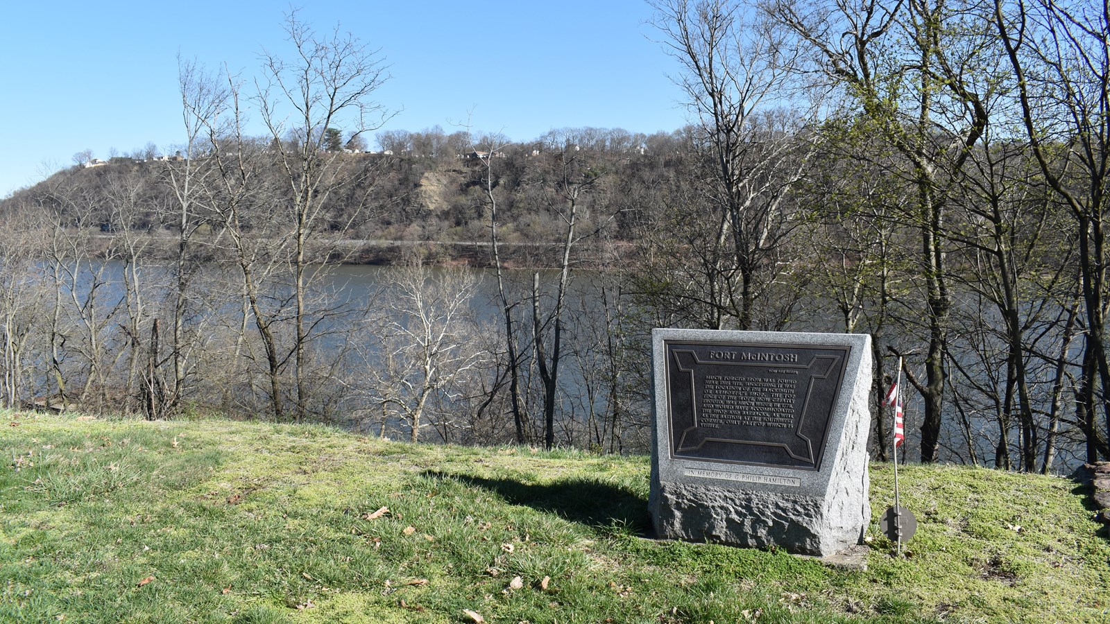 This photo shows a historical marker monument for Fort McIntosh, set on a grassy overlook above a ri