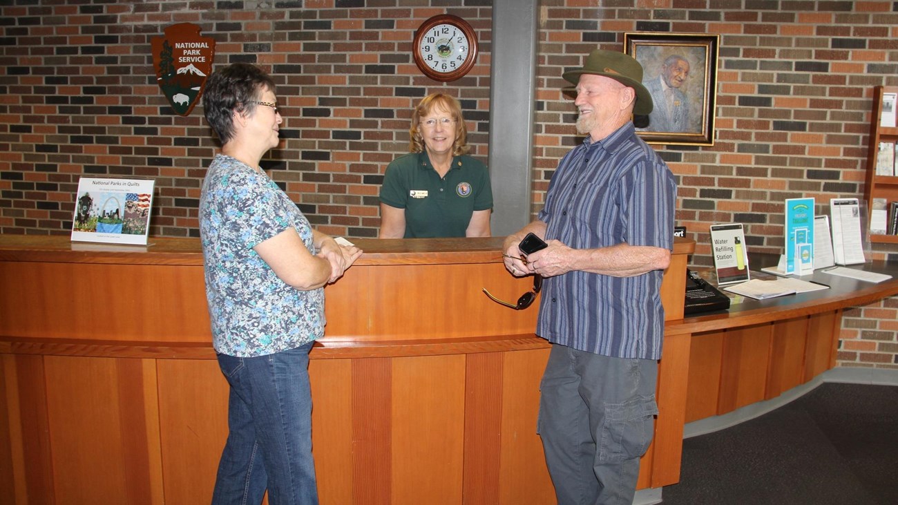 Two visitors talking to a park volunteer at the information front desk. 