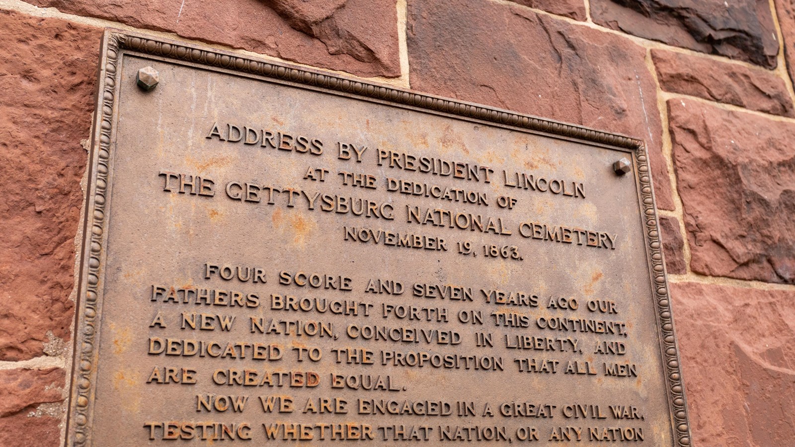 A bronze plaque on the side of a red brick building. 