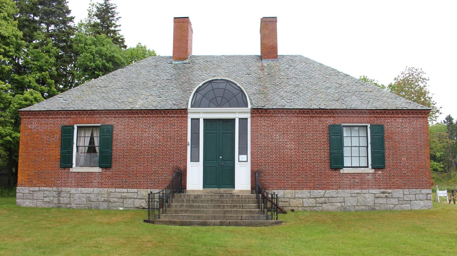 Brick building with door, two windows, chimneys, and steps