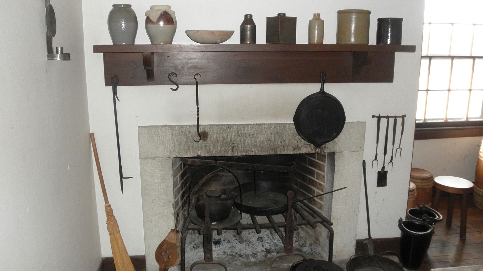 Fireplace with wooden shelf and  various implemtents to the side and above 