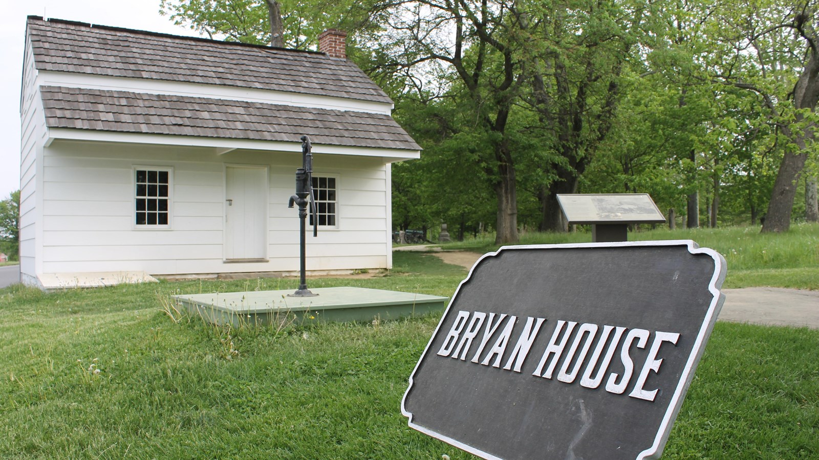 A small white onestory house with a black label reading 