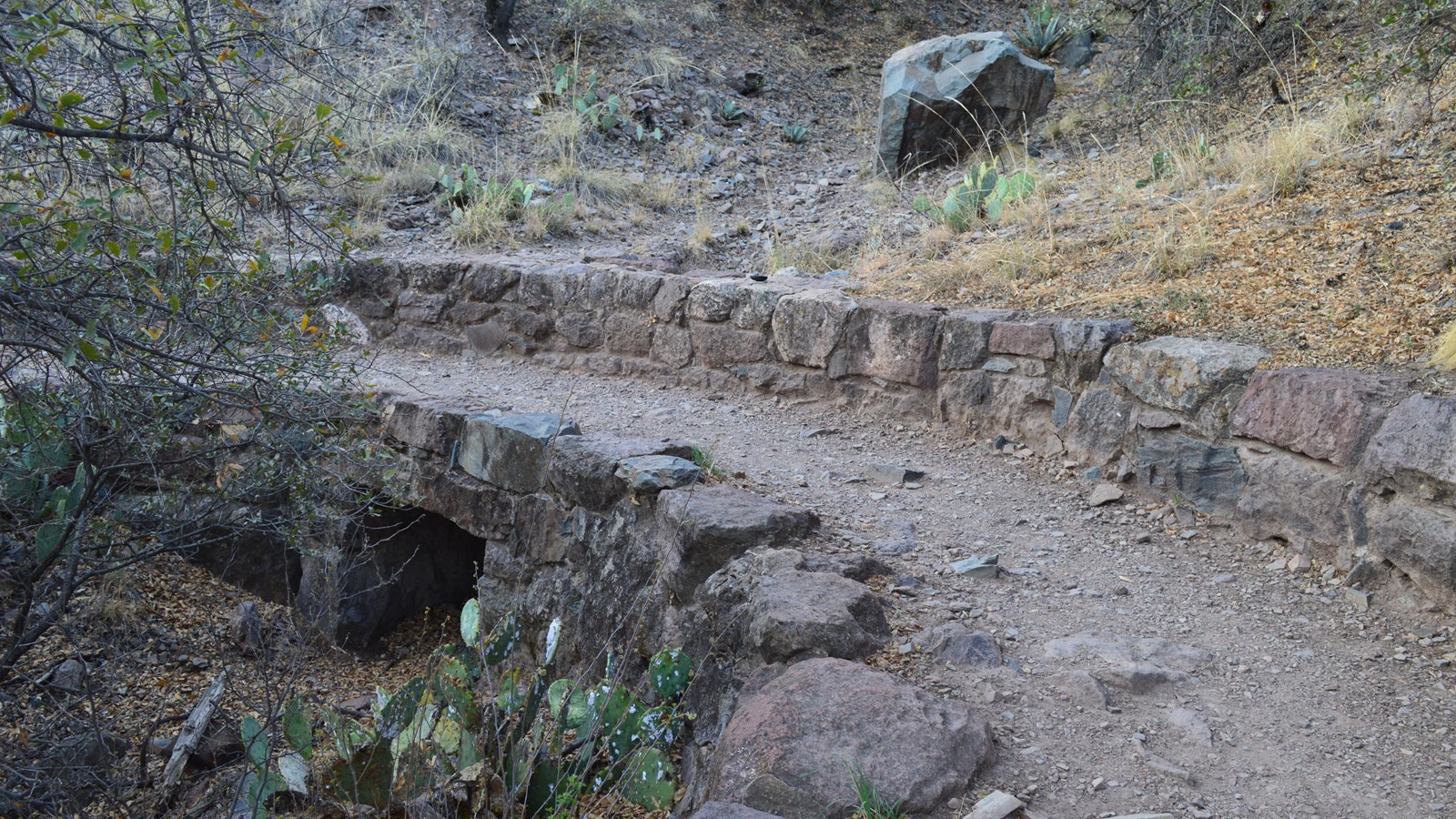 A dirt hiking trail crosses over a culvert built from local stone by the Civilian Conservation Corps