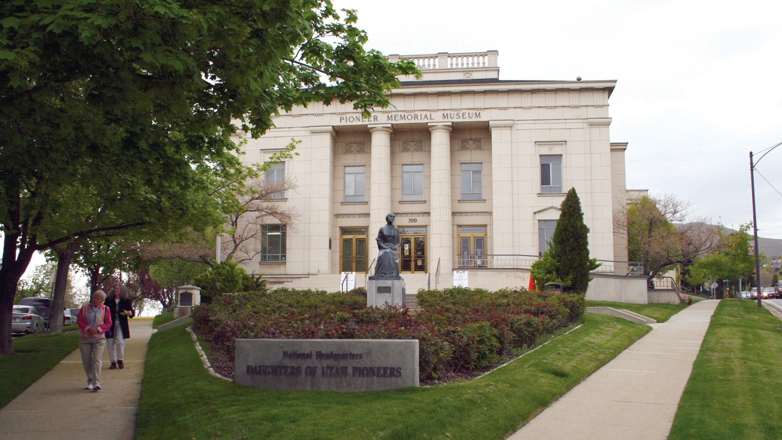 Paths lead to a large, white stone building with tall pillars at the entrance.