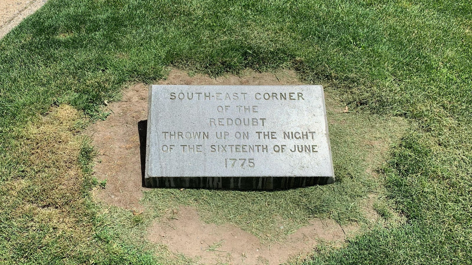 Low granite marker with engraved text in a grassy area