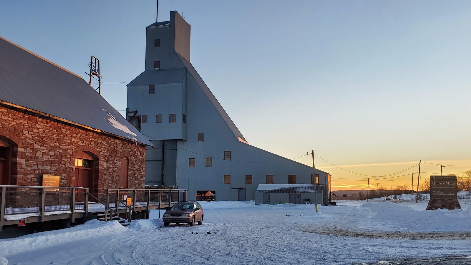 Winter scene of red and white sandstone building with snow covered parking lot.