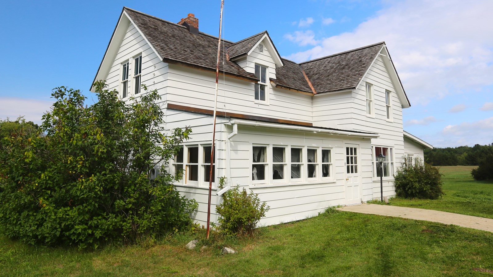 Large white, many gabled farmhouse with an enclosed front porch