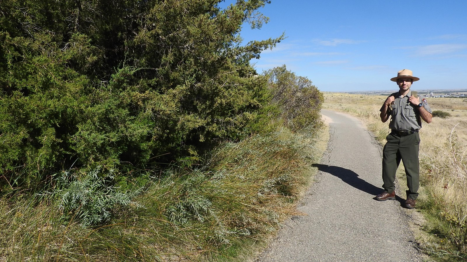 A park ranger stands near an area thick, green vegetation where a spring emerges from the ground.